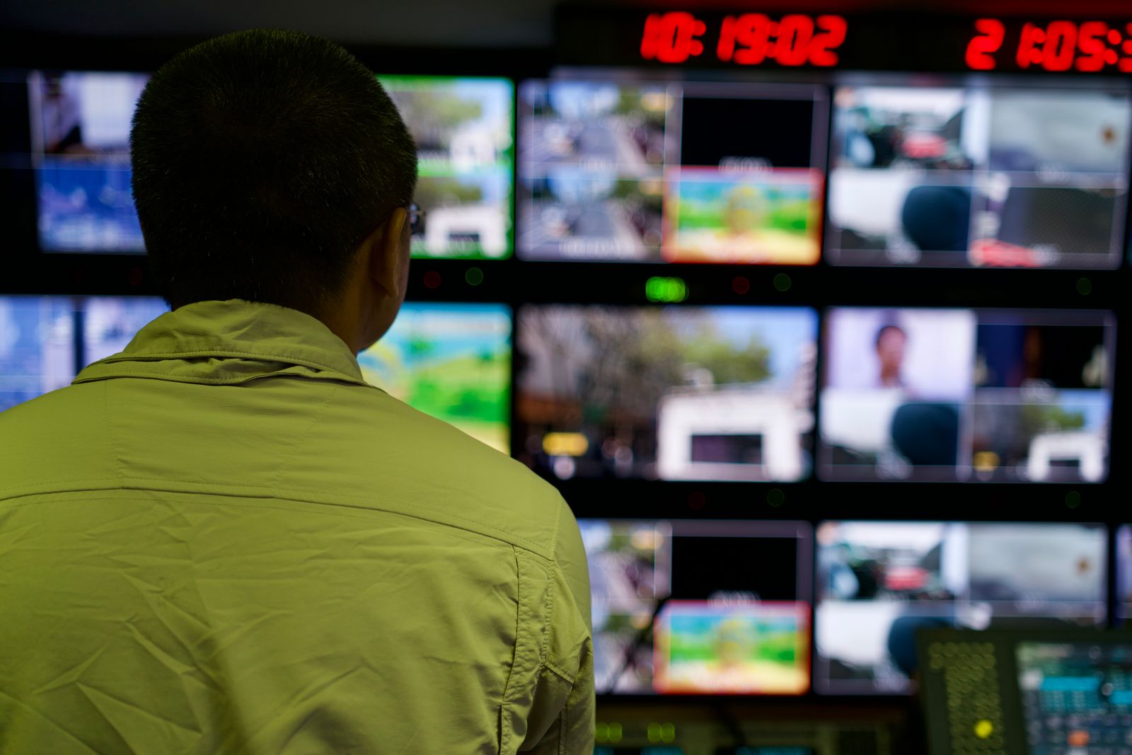 Operator monitoring multiple tactical feeds across a control room display wall